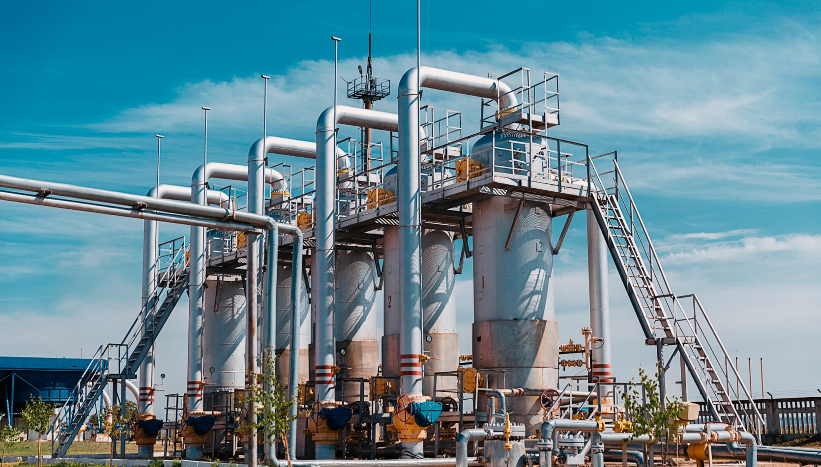 refinery with pipelines and a blue sky with clouds in background x