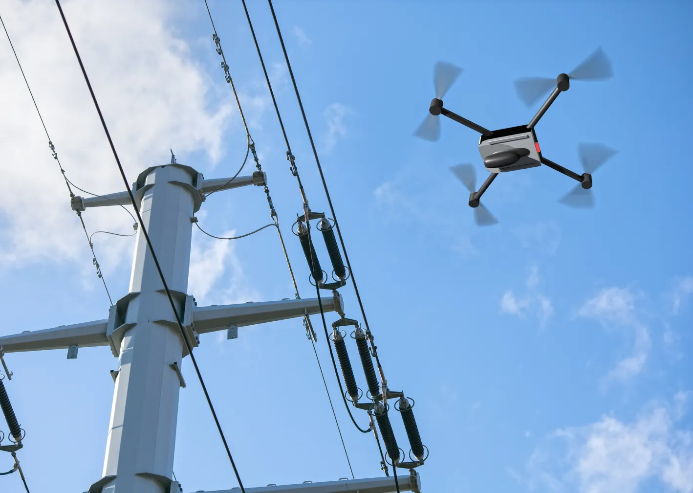 A drone flies close to a tall utility pole with power lines against a blue sky. The drone has four rotors and a sleek, modern design. The utility pole features several insulators and wires.